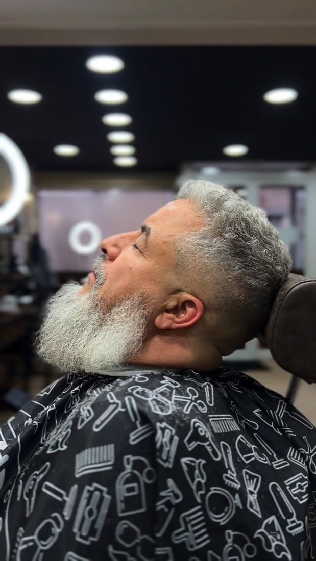 Client installé dans le fauteuil du salon Chezel Barber pendant le travail de la barbe